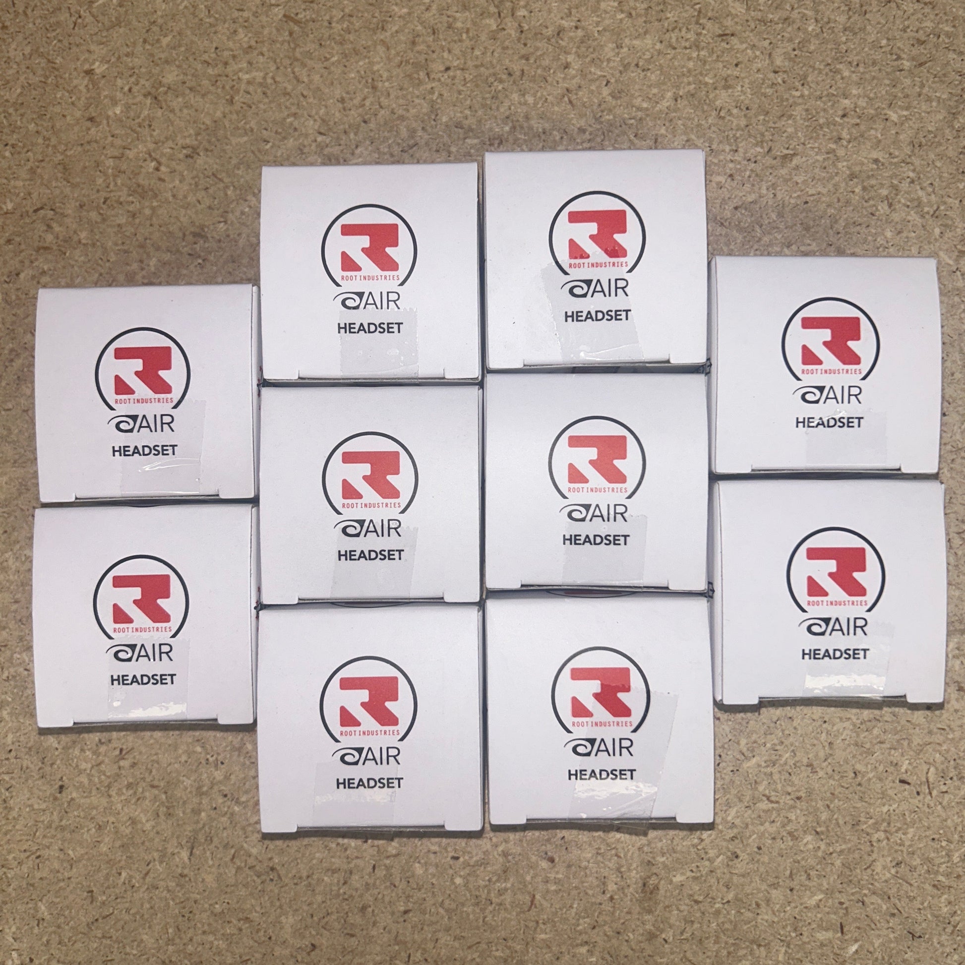 10 boxes of Root Industries AIR Headset are arranged in a pyramid formation on a brown surface.